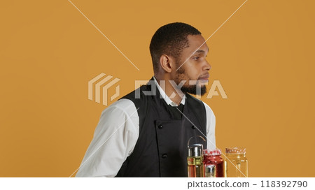 Waiter bringing drinks in glasses on a tray for clients at a table, serving lemonade to customers before their dinner. Professional staff serving people at a five star restaurant. Camera A. 118392790