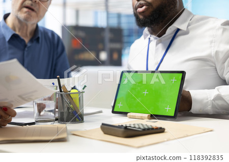 Broker specialist presents financial options for senior people next to isolated mockup, exploring retirement plans available for future family expenses. Elderly couple receive counseling. 118392835