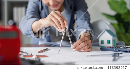 Architect Using a Compass for Precise Blueprint Design in Construction Planning Architect Using a Compass for Precise Blueprint Design in Construction Planning 118392937