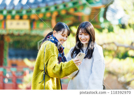 Two women taking a commemorative photo at a tourist spot Two women taking a commemorative photo at a tourist spot 118392970