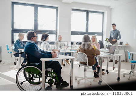 Teacher explaining senior students how to work with laptop and internet. Elderly people attending computer and technology education class. Digital literacy. 118393061