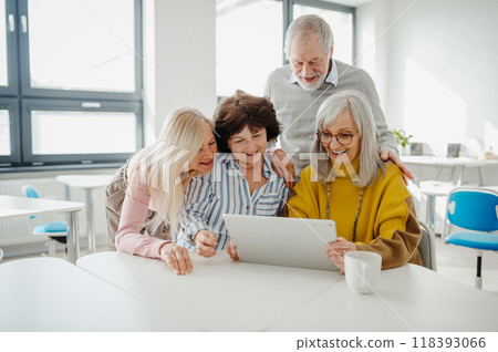 Group of senior students looking at tablet screen, learning new skill. Elderly people attending computer and technology education class. Digital literacy. Group of senior students looking at tablet screen, learning new skill. Elderly people attending computer and technology education class. Digital literacy. 118393066