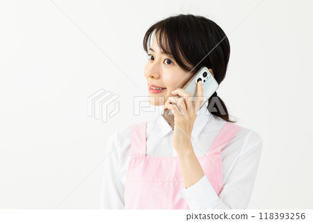 Asian woman in an apron making a phone call 02 Asian woman in an apron making a phone call 02 118393256