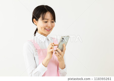 穿著圍裙的女人操作智慧型手機 03 118393261