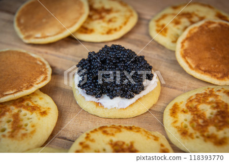 Blinis with black caviar and cream cheese, on a festive dish, mini pancakes, an elegant appetizer Blinis with black caviar and cream cheese, on a festive dish, mini pancakes, an elegant appetizer 118393770