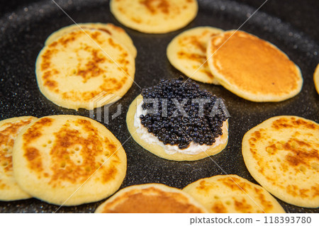 Blinis with black caviar and cream cheese, on a festive dish, mini pancakes, an elegant appetizer 118393780