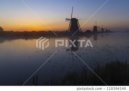 Traditional Dutch windmills with a colourful sky just before sunrise in Kinderdijk, The Netherlands Traditional Dutch windmills with a colourful sky just before sunrise in Kinderdijk, The Netherlands 118394140