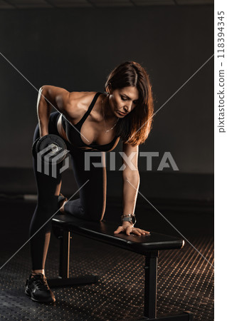 A vibrant portrait of a dedicated female athlete focused on strength training with a dumbbell. It showcases her athleticism, resilience, and commitment to health, reflecting her empowering journey A vibrant portrait of a dedicated female athlete focused on strength training with a dumbbell. It showcases her athleticism, resilience, and commitment to health, reflecting her empowering journey 118394345