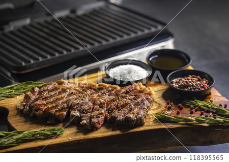 ribeye steak on wooden board with spices and electric grill 118395565