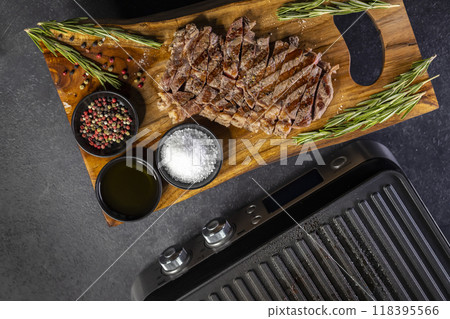 ribeye steak on wooden board with spices and electric grill ribeye steak on wooden board with spices and electric grill 118395566