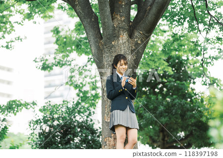 A high school girl looking at her smartphone in the shade 118397198