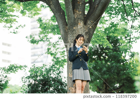 A high school girl looking at her smartphone in the shade A high school girl looking at her smartphone in the shade 118397200