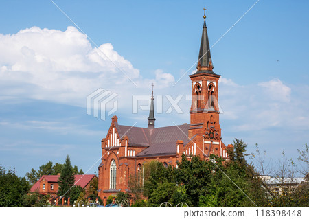A large red brick church building with an elegant steeple surrounded by trees A large red brick church building with an elegant steeple surrounded by trees 118398448