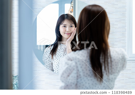 一個女人在鏡子裡檢查她的皮膚狀況 118398489
