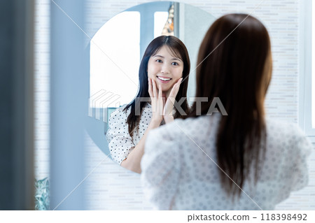 一個女人在鏡子裡檢查她的皮膚狀況 118398492