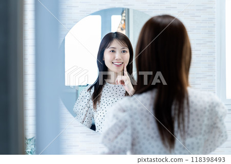 一個女人在鏡子裡檢查她的皮膚狀況 118398493