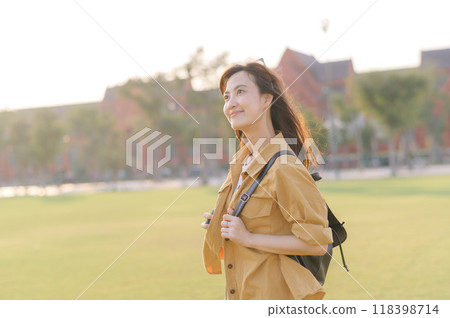 Traveler asian woman in her 30s stands bathed in the golden glow of sunset, embracing the freedom of exploration. on summer holiday weekend vacation trip in Bangkok, Thailand 118398714
