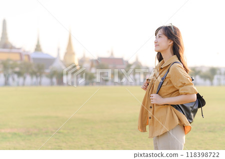 A Traveler Asian woman in her 30s exploring Wat Pra Kaew. From stunning architecture to friendly locals, she cherishes every moment, capturing it all in her heart and camera for years to come. 118398722