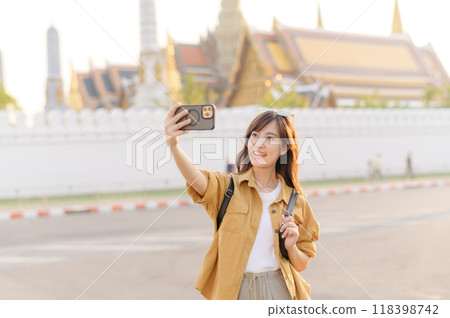 Traveler asian woman in her 30s explores the Grand Palace with a local guide. Uncover hidden gems and immerse yourself in Thai culture with her adventure. 118398742