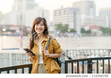 young Asian woman in 30s on a solo adventure. Technology in hand, she captures the essence of cultural exploration and joyful discovery. young Asian woman in 30s on a solo adventure. Technology in hand, she captures the essence of cultural exploration and joyful discovery. 118398786