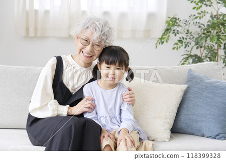 Grandmother snuggling with her grandson in the living room, looking at the camera Grandmother snuggling with her grandson in the living room, looking at the camera 118399328
