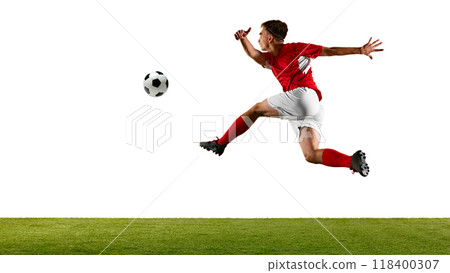 Young footballer in red and white, leaping high to control ball, performing skillful header during football training on green field in studio. Young footballer in red and white, leaping high to control ball, performing skillful header during football training on green field in studio. 118400307