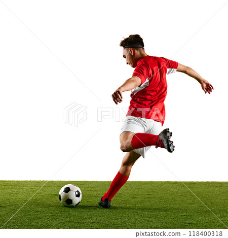 Focused sportsman, dressed in red and white, performing dynamic strike on ball during football training against white studio backdrop. 118400318