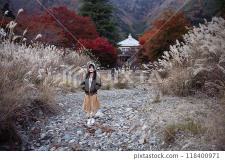 Asian woman in casual dress embraces the beauty of Japan's autumn. A holiday portrait capturing friends, selfies, and joyful moments by the lake near Mount Fuji. 118400971
