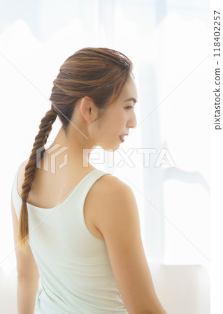 A young woman laying a mat in preparation for an online yoga salon A young woman laying a mat in preparation for an online yoga salon 118402257