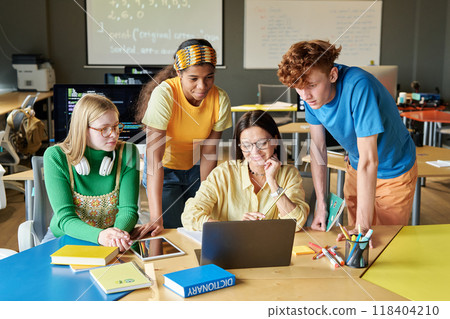 Group of young people collaborating on software with young woman as female teacher at IT class in school or college 118404210