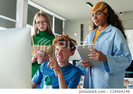 Three students collaborating on project using computer in team during IT class in school or college 118404246