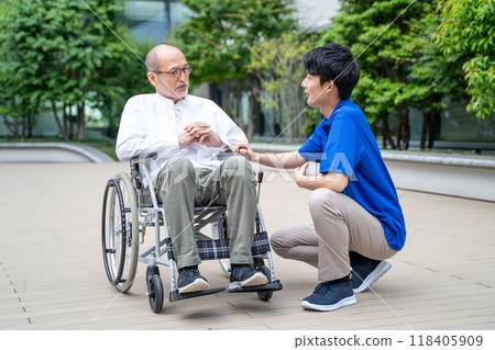 Senior man in wheelchair and care facility staff 118405909