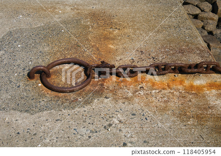 Rusty chain attached to an anchor attached to a dike Rusty chain attached to an anchor attached to a dike 118405954