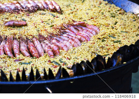 A sizable pan brimming with rice and shrimp, sizzling on a grill A sizable pan brimming with rice and shrimp, sizzling on a grill 118406918