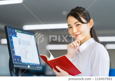Young business woman checking a notebook in the office Young business woman checking a notebook in the office 118407802