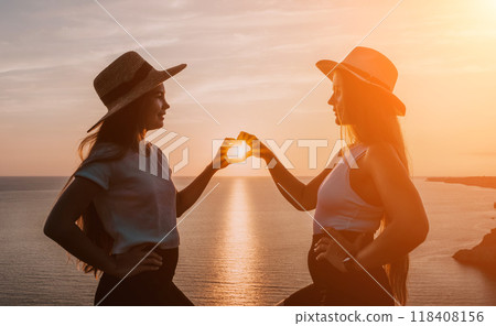 Silhouettes of Two Women Making Heart Shape at Sunset 118408156