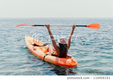Kayaking Woman Ocean Paddle Happy - A woman paddles a kayak in the ocean with her arms raised in the air. 118408181