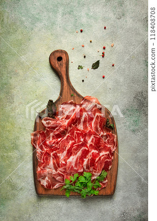 Prosciutto on a cutting board, top view, appetizer, breakfast, spices and herbs, 118408708