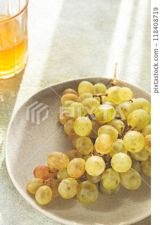 a branch of white grapes, on a gray plate, with a glass of white wine, top view, natural light, food concept, no people, 118408719