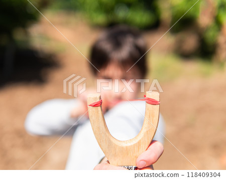 Child aiming slingshot outdoors in focus 118409304