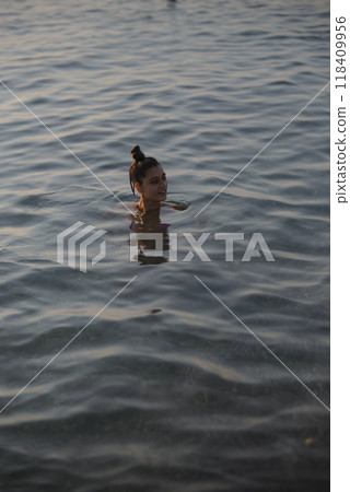Enjoying a Serene Evening Swim in the Calm Waters of a Picturesque Lake at Sunset Enjoying a Serene Evening Swim in the Calm Waters of a Picturesque Lake at Sunset 118409956