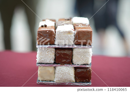 Chocolate and Coconut-Covered Cubed Desserts Stacked on Maroon Surface Chocolate and Coconut-Covered Cubed Desserts Stacked on Maroon Surface 118410065