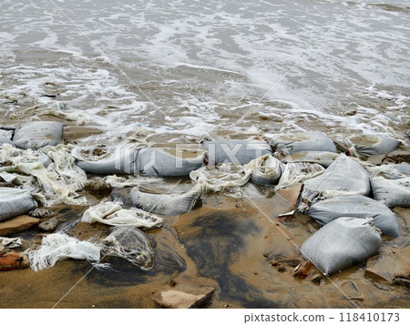 Trash scattered all over the beach close to the ocean 118410173