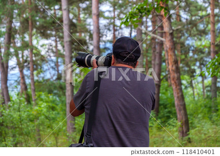 Nature photographer capturing wildlife in lush forest during daytime 118410401