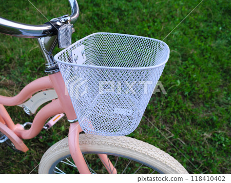 Closeup of a pastel bicycle with a metal basket on a sunny grassy field Closeup of a pastel bicycle with a metal basket on a sunny grassy field 118410402