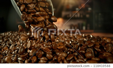 Close-up of roasted coffee beans falling from a steel spoon. Close-up of roasted coffee beans falling from a steel spoon. 118410588