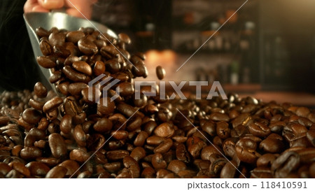 Man throwing roasted coffee beans from a steel spoon. 118410591