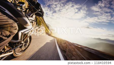 Motorbiker riding in Alps, dramatic sky. Travel and freedom, outdoor activities Motorbiker riding in Alps, dramatic sky. Travel and freedom, outdoor activities 118410594