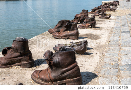 Budapest, Hungary. 25 August 2022. Memorial to the victims of the Nazi repression. Rusty metal copies of old shoes on the Danube River embankment. Holocaust and Nazi terror memory concept. Budapest, Hungary. 25 August 2022. Memorial to the victims of the Nazi repression. Rusty metal copies of old shoes on the Danube River embankment. Holocaust and Nazi terror memory concept. 118410769