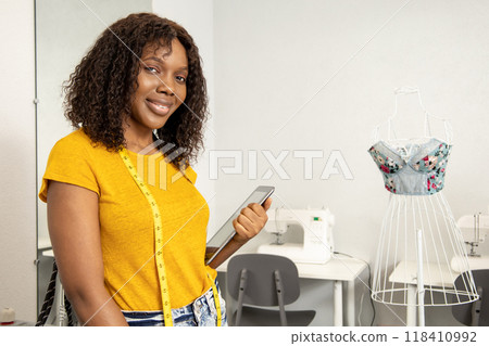 Fashion designed working in her studio and looking confident and contented Fashion designed working in her studio and looking confident and contented 118410992